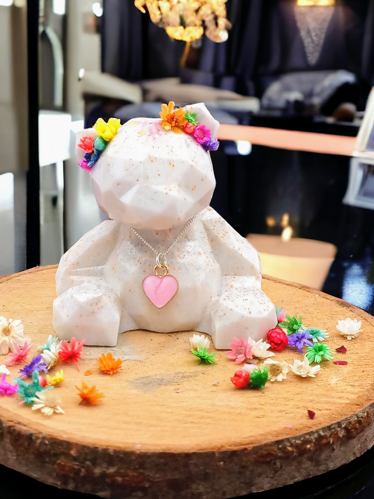 little resin bear, casted in white and pink glitter, she has dried flowers in front of her ears and pink golden heart chain around her neck  