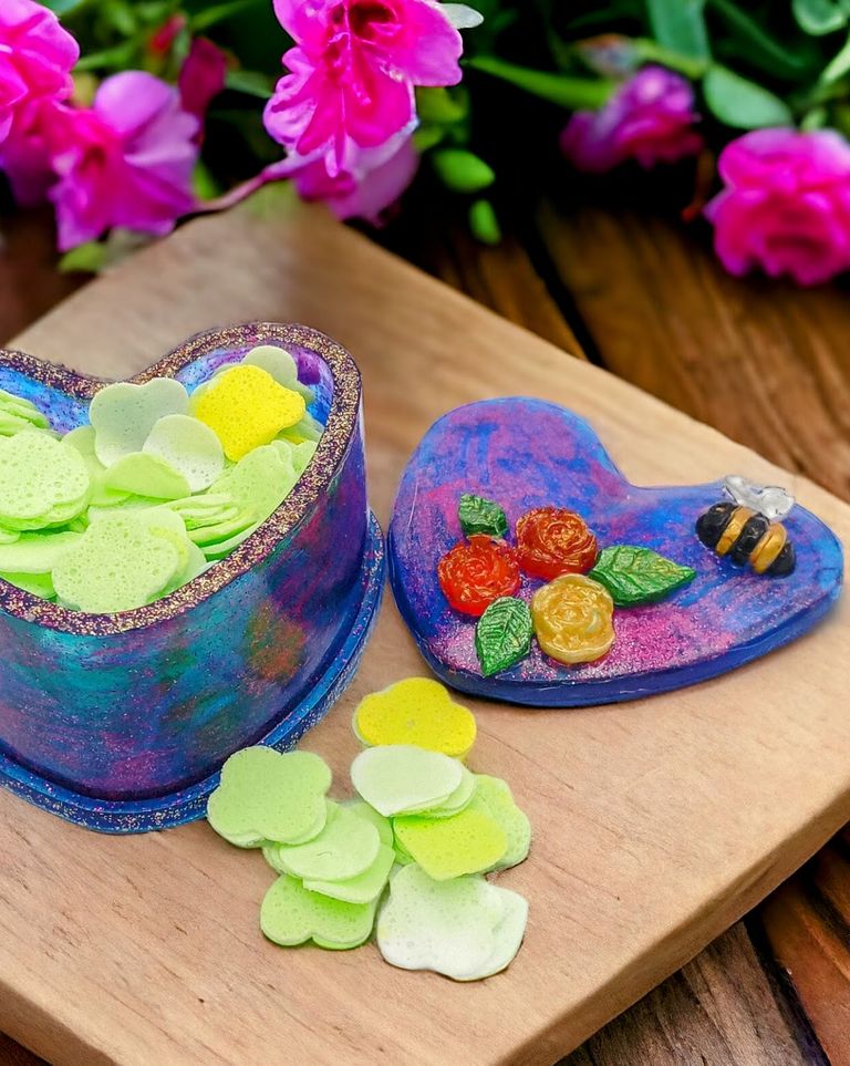 a blue n pink resin heart shape box, with soap confetti inside, on the lid of the box is resin flowers and bees 